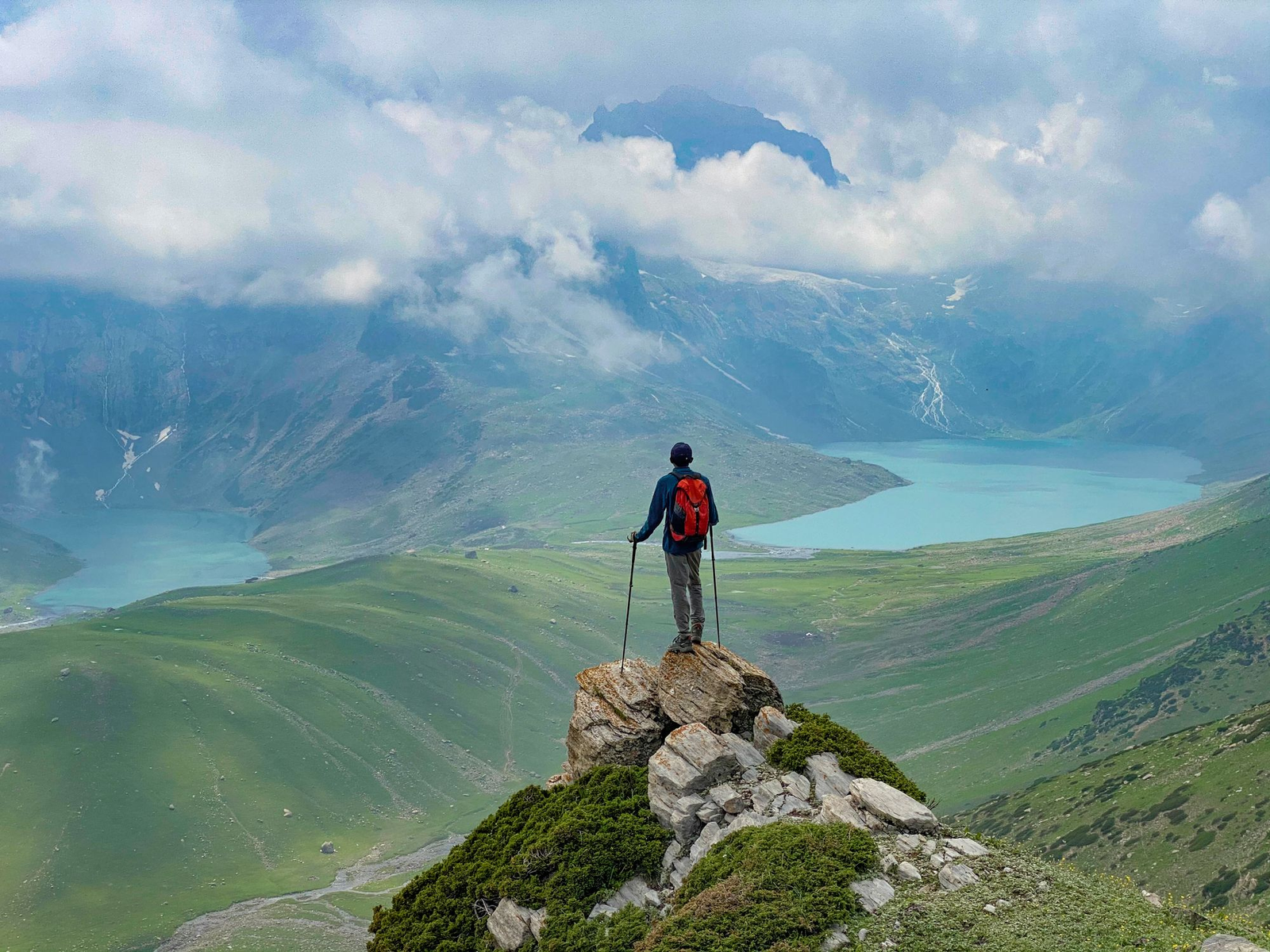 Trekking in Kashmir with a hiker overlooking alpine lakes and lush green valleys